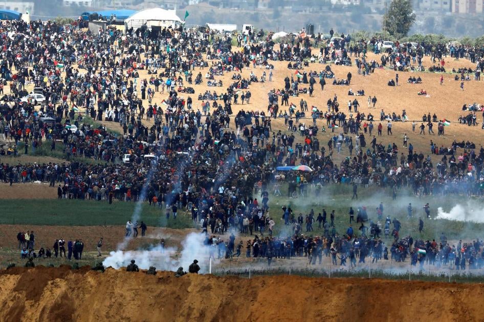  قوات إسرائيلية تطلق الغاز المسيل للدموع على متظاهرين فلسطينيين بالقرب من السياج الفاصل بين غزة وإسرائيل، كما يبدو من الجانب الإسرائيلي في 30 مارس/آذار 2018. 