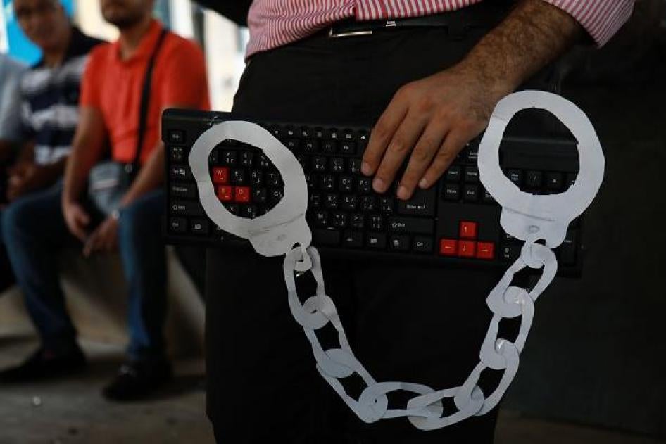 An activist holds a computer keyboard and makeshift handcuffs in downtown Beirut on July 24, 2018, during a protest against the recent wave of interrogations by Lebanese security forces of people making political comments online. 