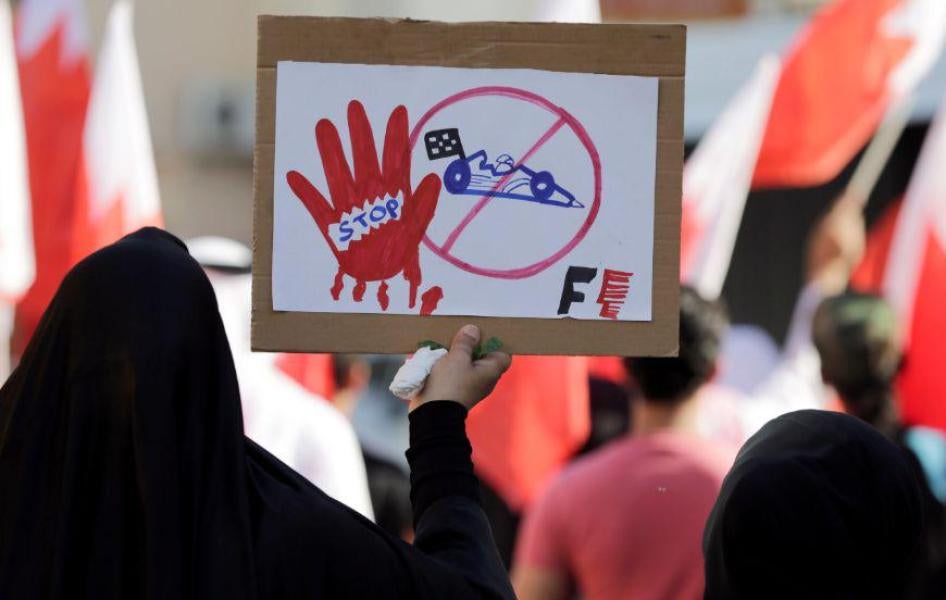 متظاهرة بحرينية تحمل لافتة تعارض سباق "الجائزة الكبرى" لـ "الفورمولا 1" في البحرين، في دايح، البحرين، الأحد 3 أبريل/نيسان 2018. 