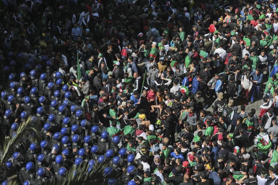 محتجون يواجهون أعوان الشرطة خلال مظاهرة ضد قيادة البلاد في الجزائر العاصمة، الجمعة، 12 أبريل/نيسان 2019. 