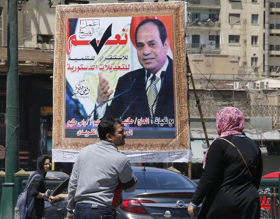 People walk past a banner supporting proposed amendments to the Egyptian constitution with a poster of Egyptian President Abdel Fattah al-Sisi  in Cairo, Egypt, Tuesday, April 16, 2019. © 2019 AP Images/Amr Nabil