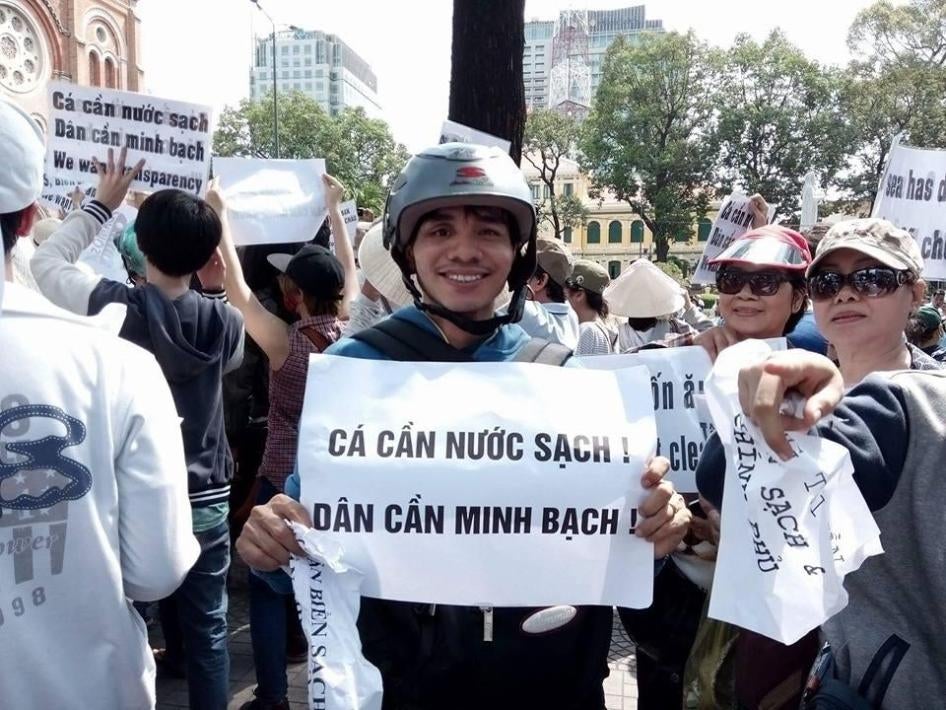 Nguyen Ngoc Anh at an anti-Formosa protest in 2016. The signs he is holding say: Fish Need Clean Water, People Need Transparency.  