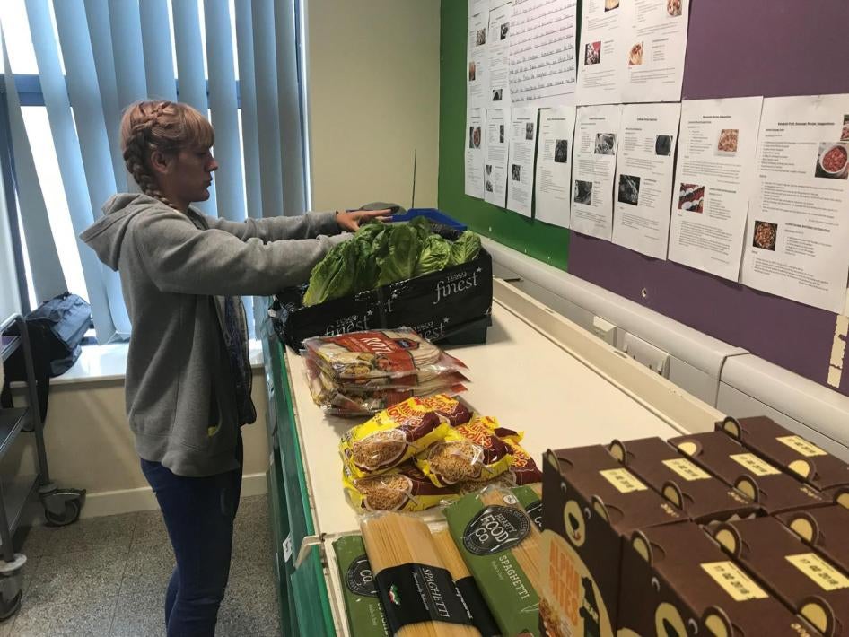 “Sarah Nor,” a volunteer and pantry user at the Goodwin Community Pantry in Hull, puts fresh produce on the shelves, June 2018. The pantry receives redistributed food from a local scheme and makes it available to community members at low cost.