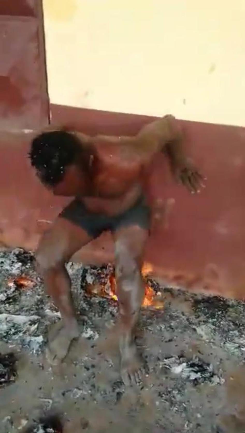Capture d’écran d'une vidéo montrant un homme forcée à s’asseoir sur des morceaux de papier enflammés, ans une école abandonnée à Bali dans la région du Nord-Ouest du Cameroun. Il aurait été torturé par des séparatistes armés dans cette région anglophone,
