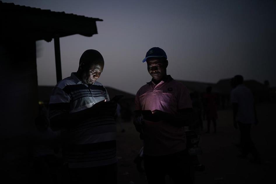 Two men check their phones in Kaduna, Nigeria