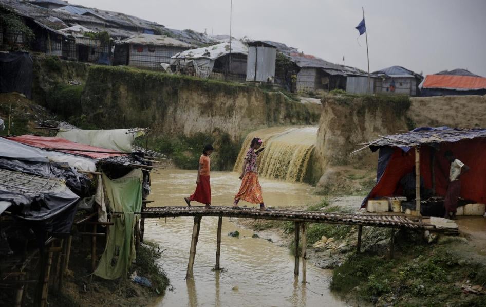 Rohingya refugee girls cross a makeshift bamboo bridge at Kutupalong refugee camp, where they have been living amid uncertainty over their future after they fled Myanmar to escape violence a year ago, in Bangladesh, Tuesday, Aug. 28, 2018.