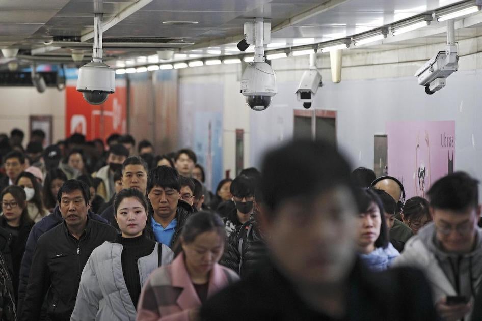 Commuters walk by surveillance cameras installed at a walkway in between two subway stations in Beijing, Tuesday, Feb. 26, 2019. Chinese government has using the facial recognition to monitor people for it "social credit" system. 