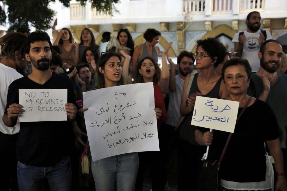 مجموعة من النشطاء اللبنانيين يرددون شعارات وهم يحملون لافتات كُتِب عليها بالعربية: "حرية التعبير" (يمين الصورة)، و "مع مشروع ليلى ضد قمع الحريات". 