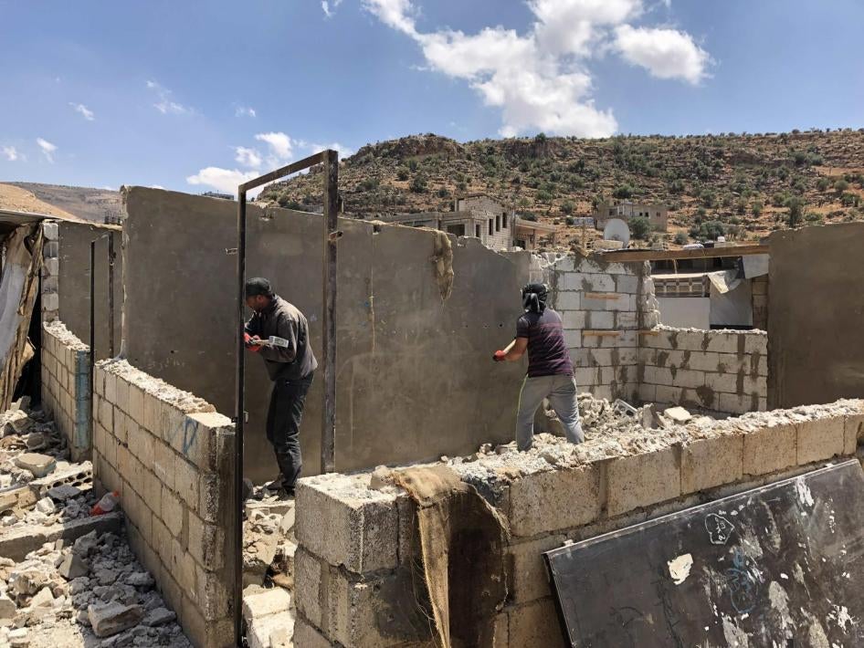 Men work to dismantle the walls of a shelter in a Syrian refugee camp in Arsal, Lebanon.