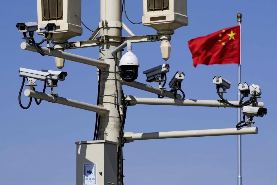 中国国旗在装满监视摄像头的灯柱后飘扬，北京，2019年3月15日。
