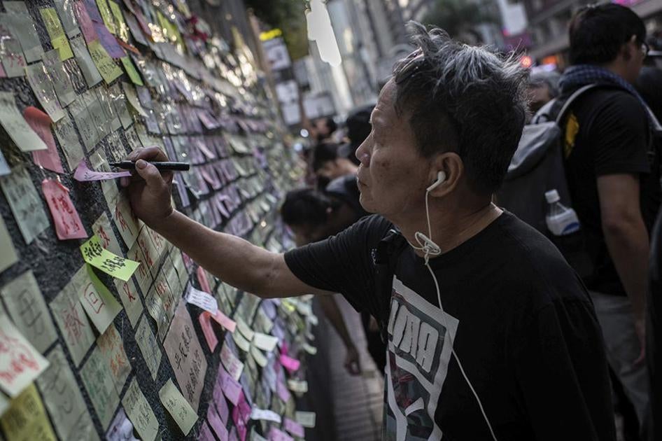 A man glues a sticker label with messages against the extradition bill and pro-democracy in a Lennon wall in Wan Chai, Hong Kong