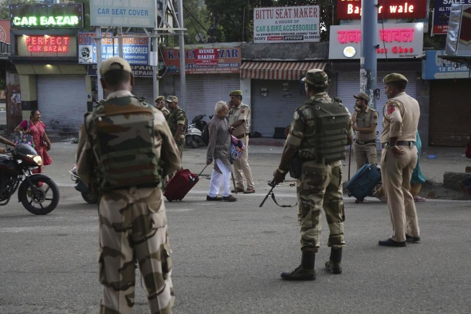 Tourists walk past Indian security forces during curfew like restrictions in Jammu, India, Monday, Aug. 5, 2019. 