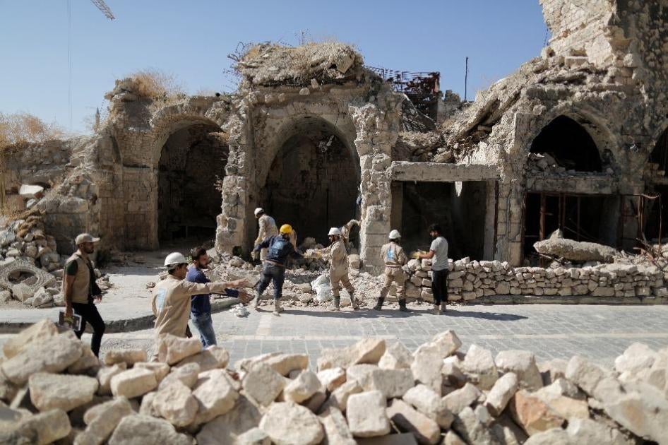 Workers remove rubble from a damaged shop in the old city of Aleppo, Syria.