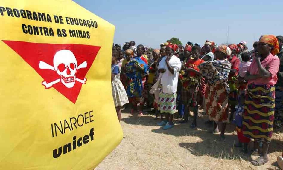 Villagers stand in front of a Unicef banner warning of landmines outside Caala, Angola