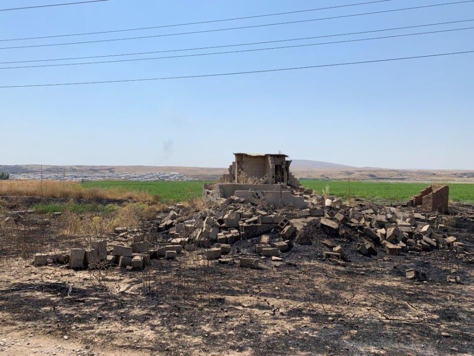 منزل مدمّر قرب قرية أش قلعة الصغير في الحمدانية، يوليو/تموز 2019. يظهر مخيّم حسن شامي في الخلفية. © بلقيس والي/هيومن رايتس ووتش.