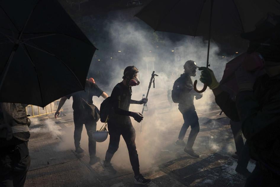 Protestors stand surrounded by smoke from tear gas shells in Hong Kong, October 1, 2019.