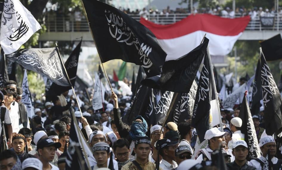 Demonstran muslim mengibarkan bendera bertuliskan: "Tiada Tuhan selain Allah dan Muhammad Adalah Rasulnya" dalam sebuah unjuk rasa di Jakarta, Indonesia, Jumat 26 Oktober 2018 