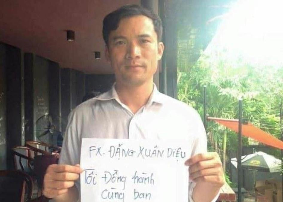 Nguyen Nang Tinh supporting the then political prisoner Dang Xuan Dieu holding a sign that reads, "Fx Dang Xuan Dieu – I accompany you." 