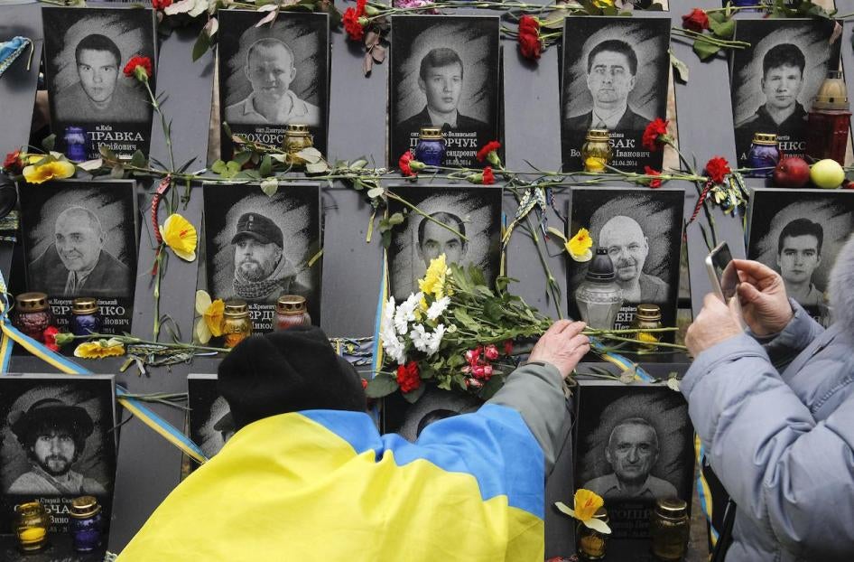 A man lays flowers to the memorial of dead Maidan activists during the anniversary in Kyiv