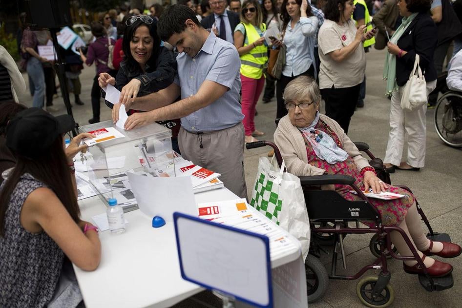 A man is helped to cast a symbolic vote during an event organized by The Spanish Committee of Representatives of Persons with Disabilities outside the Spanish parliament in Madrid, Friday, June 17, 2016.
