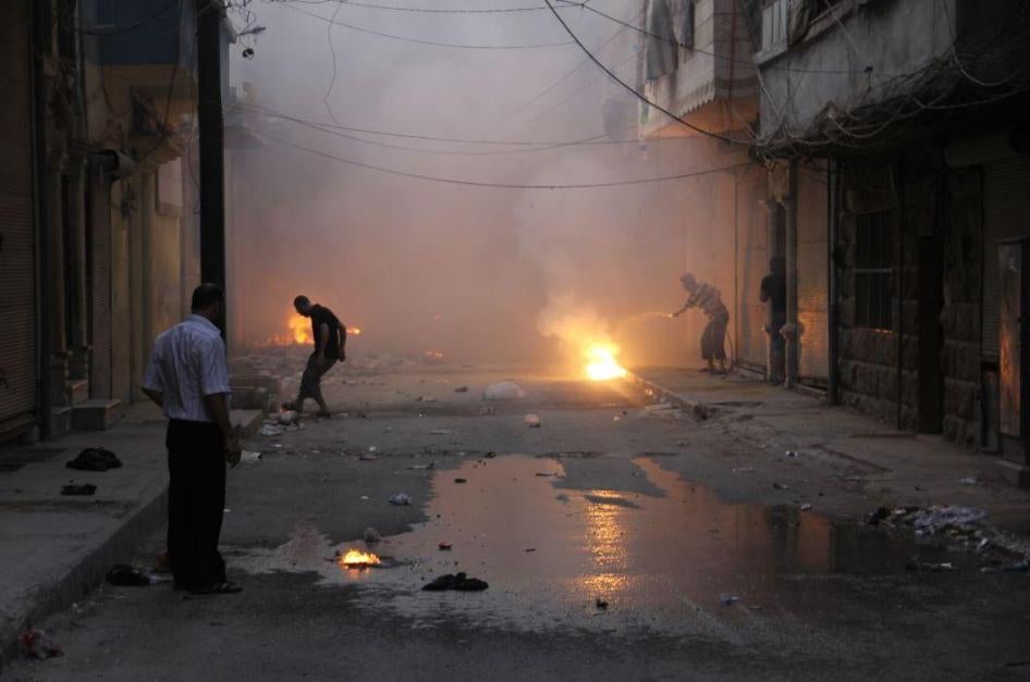 Dans une rue du quartier al-Mashhad à Alep, en Syrie, des habitants tentaient d’éteindre des feux provoqués par des sous-munitions incendiaires peu après une attaque commise le 7 août 2016.
