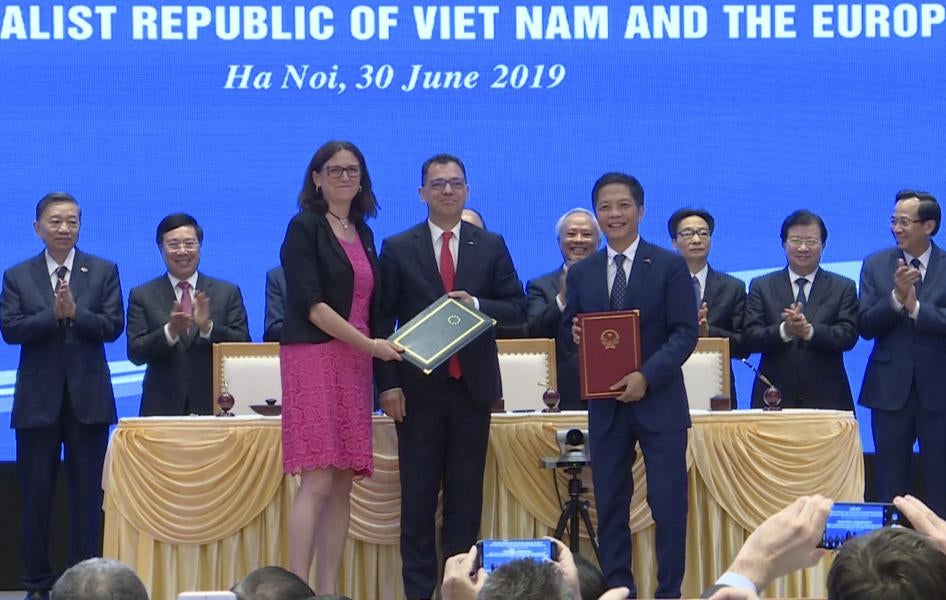 Cao ủy Liên minh châu Âu (EU) phụ trách thương mại Cecilia Malmström, phía trước bên trái, và Bộ trưởng Bộ Công thương Việt Nam Trần Tuấn Anh, phía trước bên phải, đứng và trao đổi tài liệu sau khi ký kết hiệp định thương mại tại Hà Nội vào ngày 30 tháng 