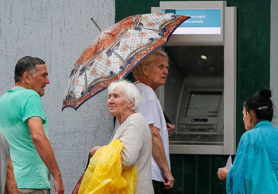 People stand near an ATM, located near the contact line between Russia-backed armed groups and Ukrainian troops in Mayorsk, Ukraine. 
