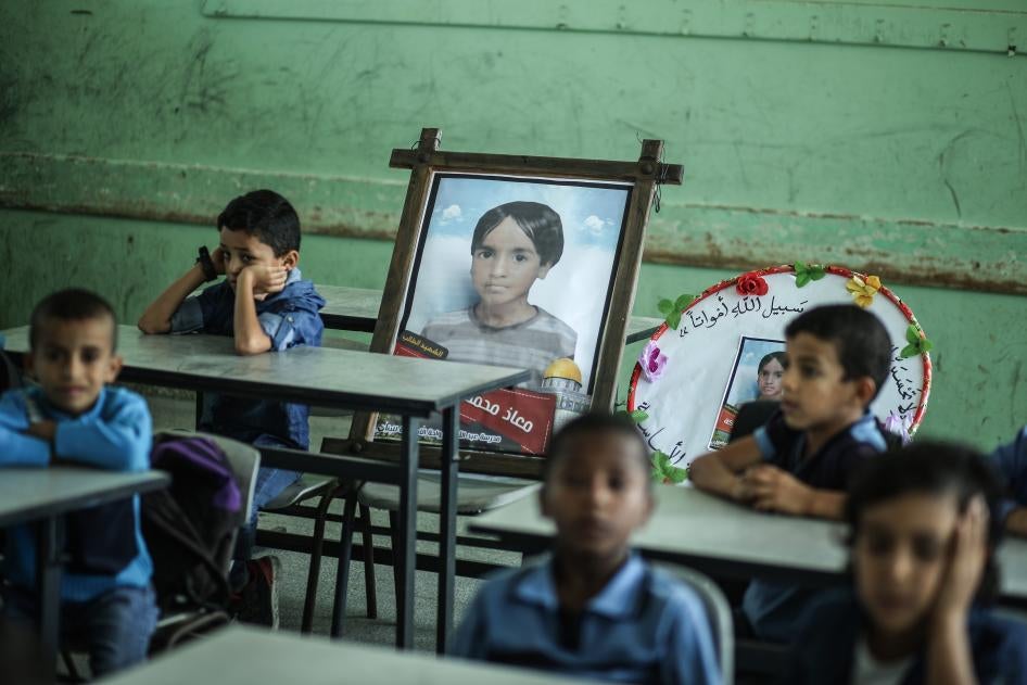 أطفال في غزة يجلسون في قاعة دراسة في 16 نوفمبر/تشرين الثاني 2019 قرب صورة لزميلهم معاذ السواركة (سبعة أعوام)، وهو أحد الأطفال الخمسة الذين كانوا قد قتلوا في غارة إسرائيلية قبل يومين.