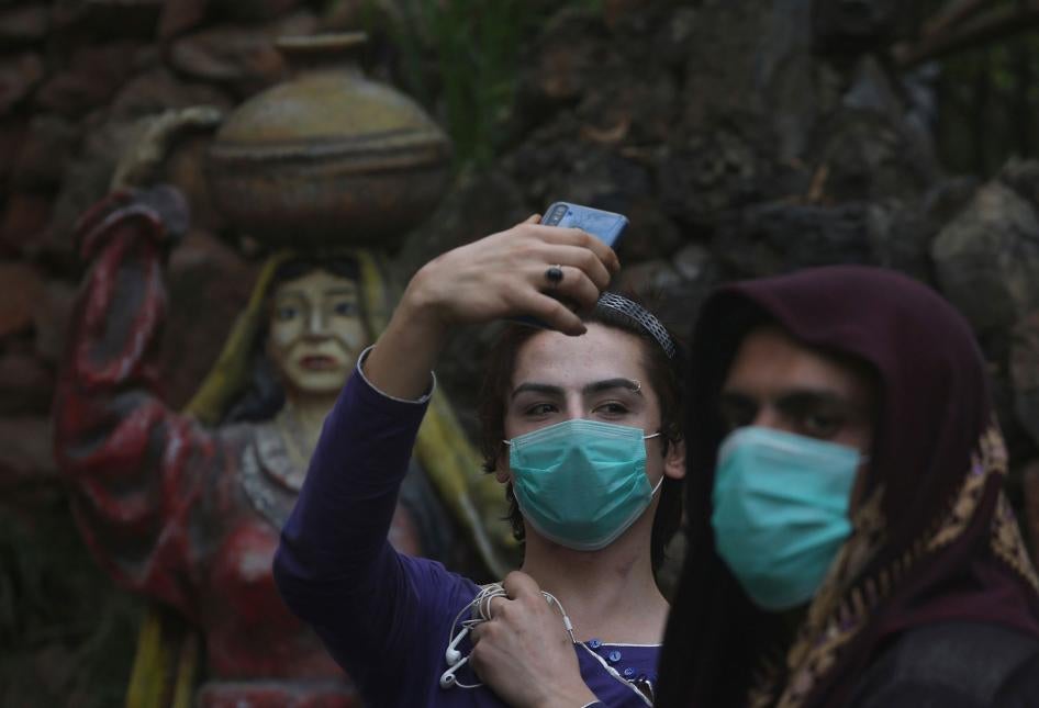 Transgender people wearing face masks as a precaution against COVID-19 take selfies at a park in Peshawar, Pakistan, March 20, 2020.