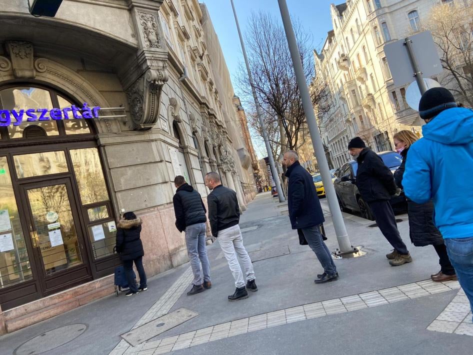 People in a line, using social distancing, in front of Budapest pharmacy” 