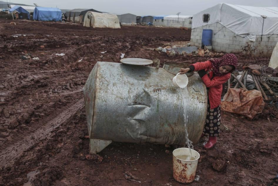 Une jeune fille syrienne recueille de l'eau conservée dans une citerne, dans un camp pour personnes déplacées qui se situe dans le nord de la Syrie, près de la frontière avec la Turquie. 