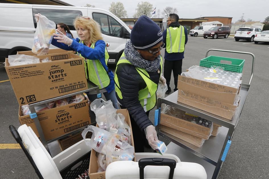 Os funcionários da escola carregam pacotes de comida enquanto distribuem refeições para alunos da Fairfield Middle School em Richmond, Virgínia, em 18 de março de 2020.