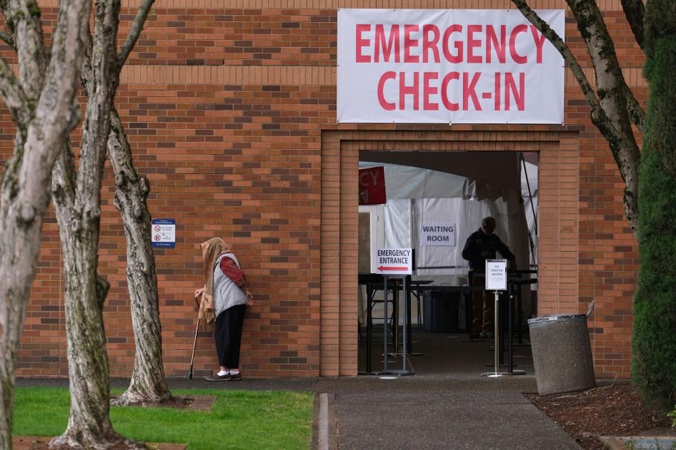 一名妇女在普罗维登斯医疗中心的急诊入口外等候，俄勒冈州，波特兰，2020年3月24日。