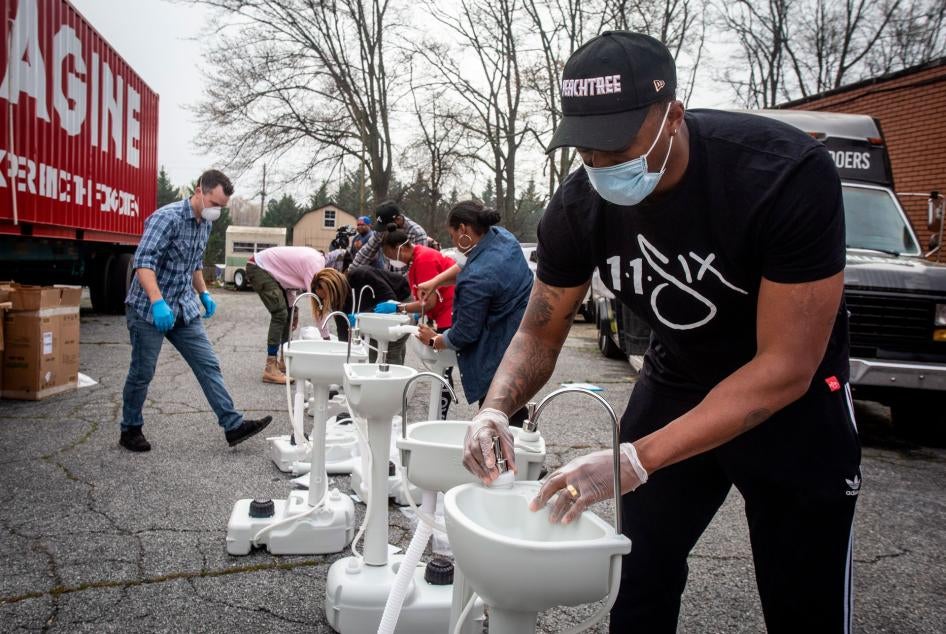 Le chanteur de hip-hop américain Lecrae (en t-shirt noir ) et des bénévoles de l’association Love Beyond Walls finissent l’assemblage de lavabos portables à College Park, en Géorgie, le 19 mars 2020. Ces lavabos portables ont ensuite été installés gratuit