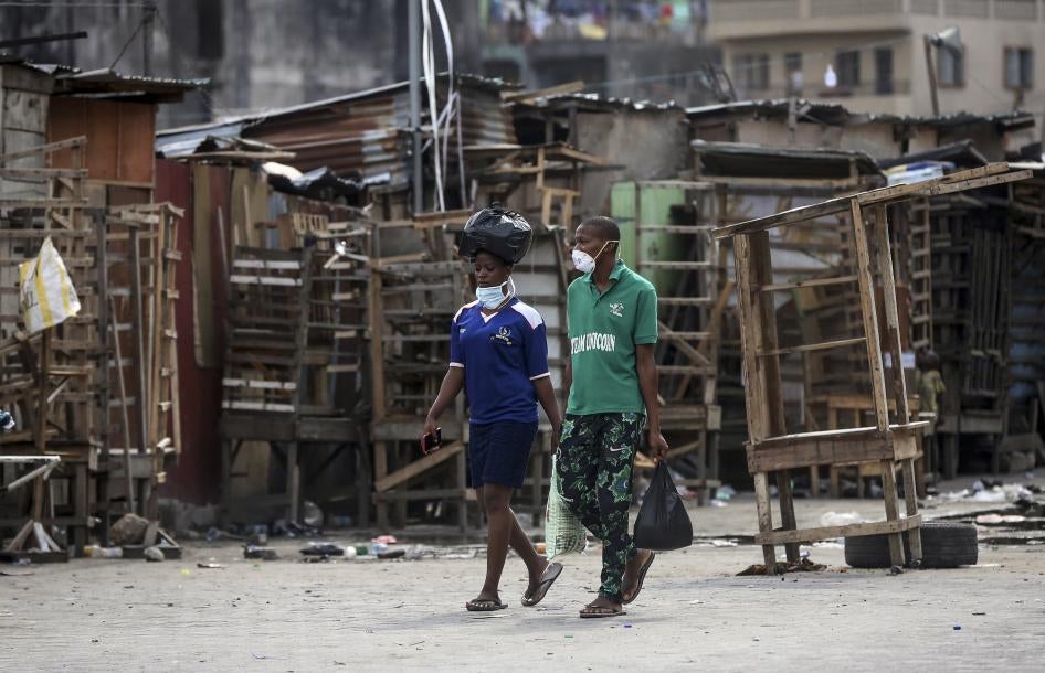 People walk past closed street stalls and shops in Lagos, Nigeria on March 26, 2020 during a government-imposed lockdown to halt the spread of COVID-19. 2020 AP Photo/Sunday Alamba.