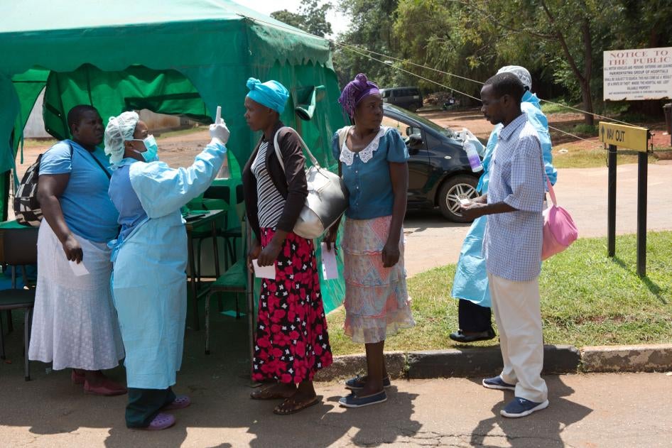 Health workers screen people visiting a public hospital in Harare, Zimbabwe, March 21, 2020.