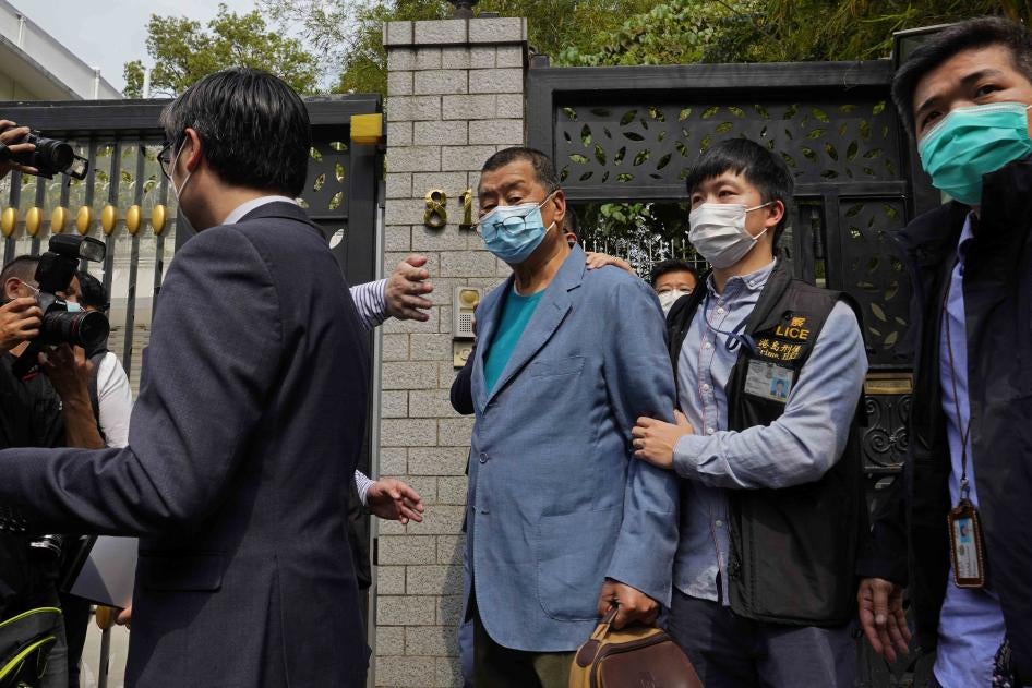 L’entrepreneur et magnat des médias Jimmy Lai (vêtu d’une veste bleue), fondateur du journal Apple Daily et connu pour son soutien au mouvement prodémocratie à Hong Kong, est escortée par des policiers l’ayant arrêté à son domicile, le 18 avril 2020.  