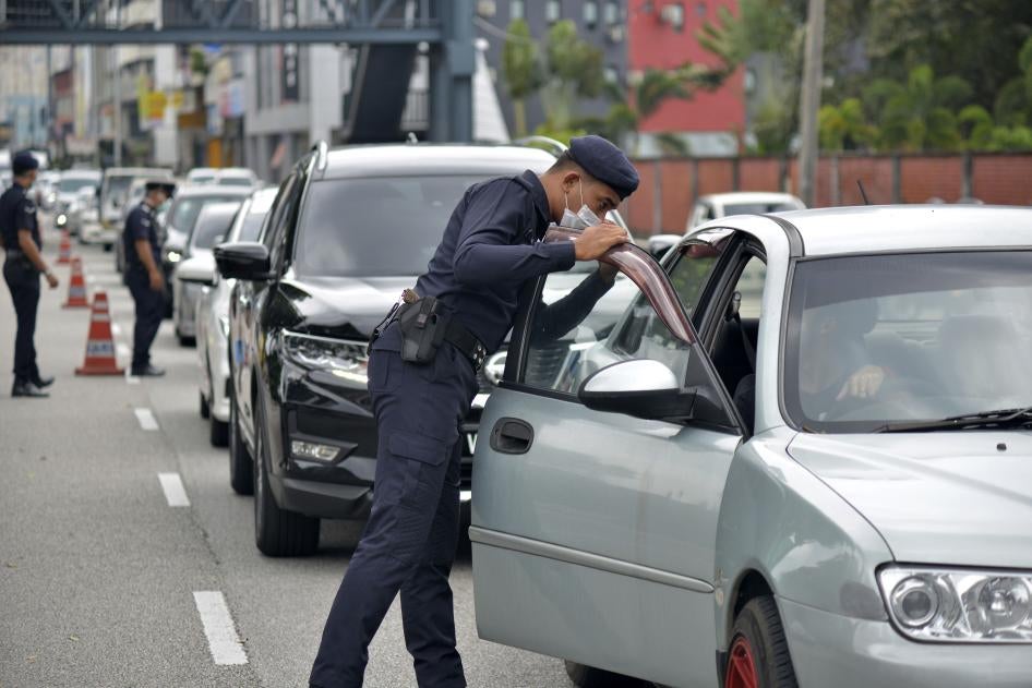 Police officers check vehicles at a roadblock to ensure that people abide by the movement control order in downtown Kuala Lumpur, Malaysia, March 19, 2020. © 2020 AP Photo