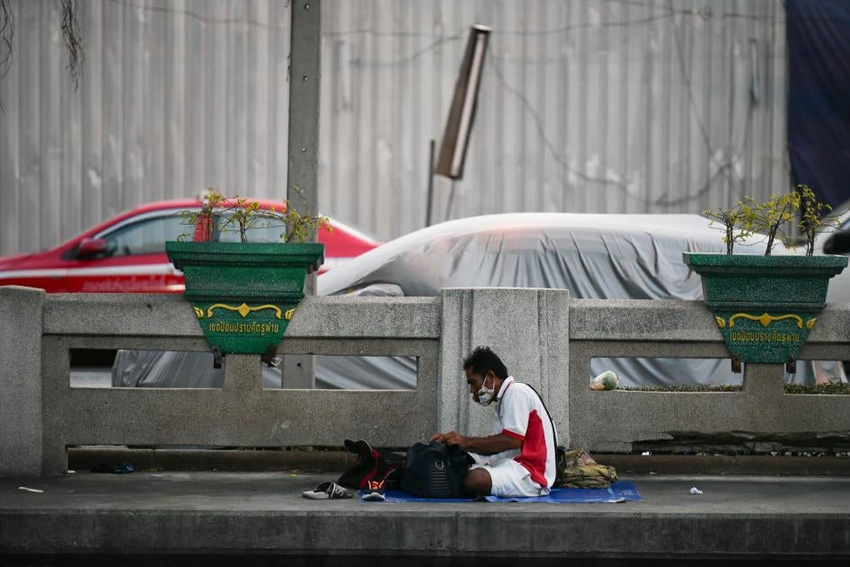 A homeless man sits beside the road outside the Hua Lamphong train station in Bangkok, Thailand, April 9, 2020.