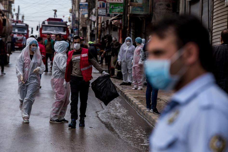 Des agents de la santé supervisent les mesures de désinfection de rues à Qamishli, dans le nord-est de la Syrie, afin d’empêcher la propagation du coronavirus, le 24 mars 2020. 