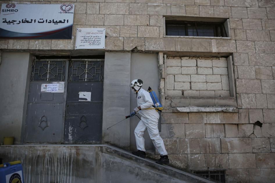 Un membre de la Défense civile syrienne, un groupe également connu sous le nom de Casques blancs, pulvérise un produit désinfectant devant la porte d'un hôpital à Idlib, en Syrie, le 22 mars 2020.
