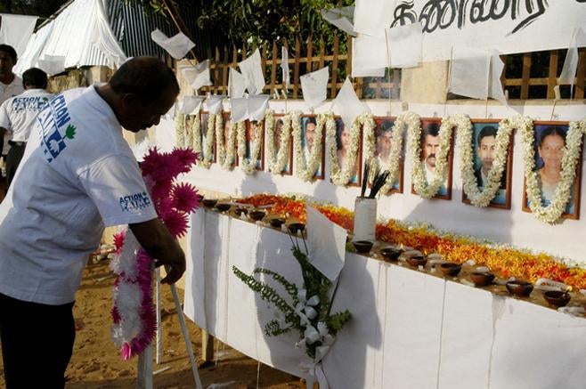 A member of the French aid group Action Contre La Faim places a wreath in front of the photographs of his 17 slain colleagues at their memorial in Batticaloa, Sri Lanka on August 11, 2006.