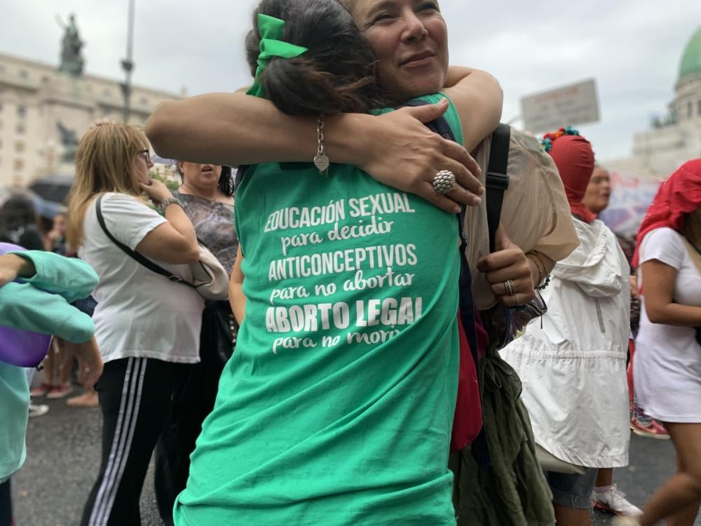 Two women hug at an outdoor rally