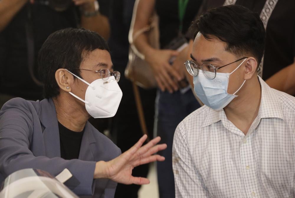 A man and a woman in medical masks speak to each other