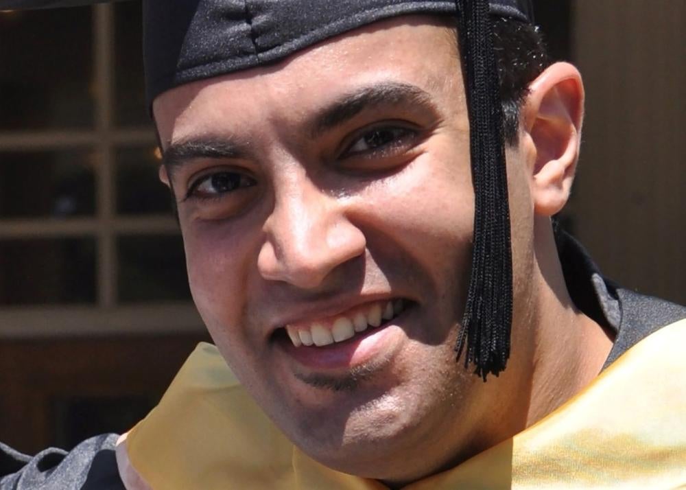 A man smiling in a university cap and gown 