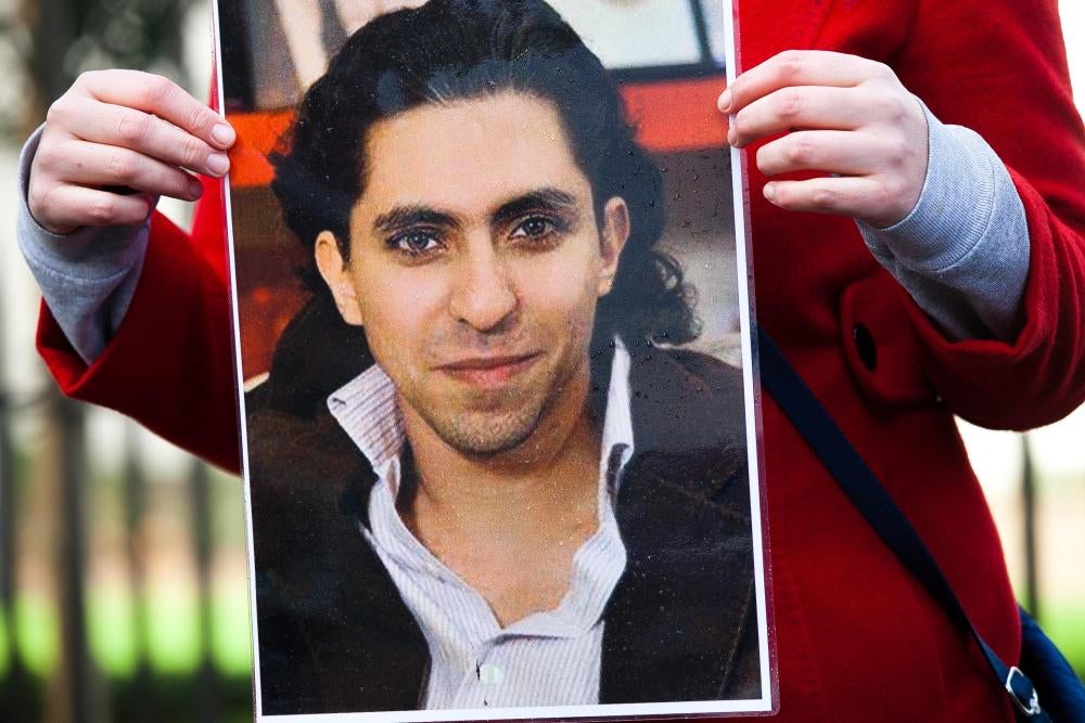 A man holding a printed photograph of Raif Badawi