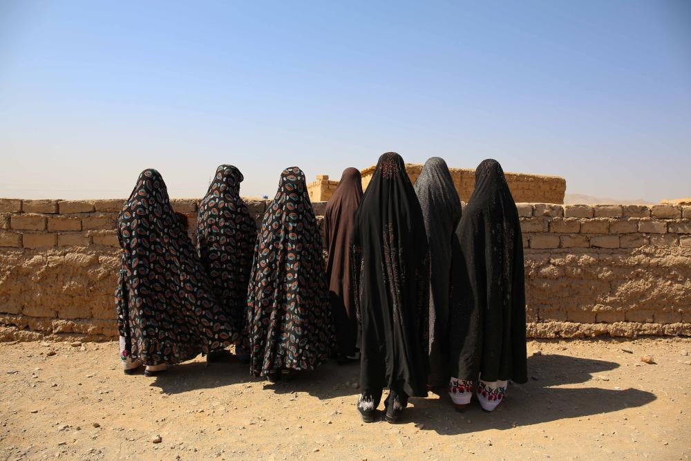 A group of women stand outside with their backs to the camera 