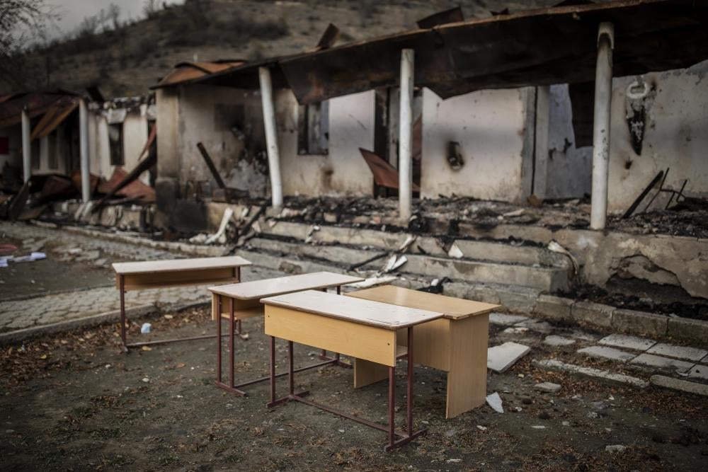 Desks in front of the remains of a charred building