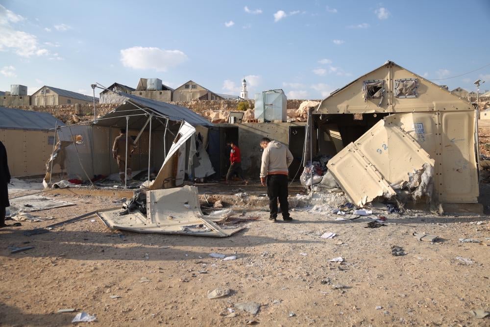 Unas personas examinan los daños causados por el ataque con municiones de racimo de la alianza militar sirio-rusa contra el campamento de Maram.
