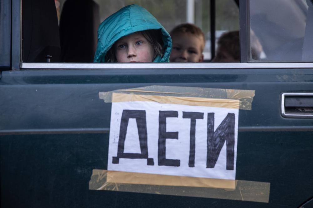Children from Mariupol, Ukraine, look out the window of their family’s car, marked with the word “children,” after arriving at an evacuation point for people fleeing areas under Russian control.